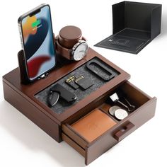 an iphone is sitting on top of a wooden box with other items in it, including a watch and earbuds