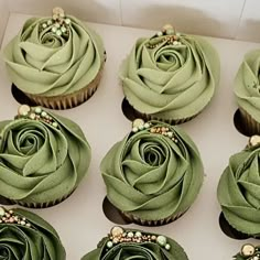 several cupcakes with green frosting and pearls on the top are arranged in a box