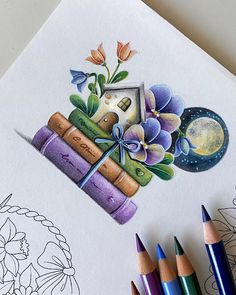 some colored pencils are laying on top of a drawing book with flowers and books