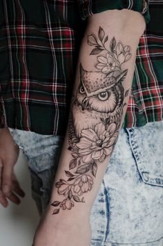 an owl and flowers tattoo on the arm