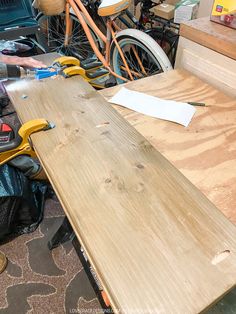 a wooden table sitting in front of a pile of tools and other things on the ground