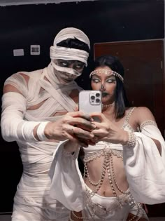 a man and woman dressed up in costumes taking a selfie with a cell phone