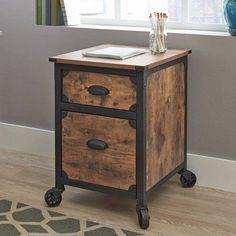 a small wooden table with two drawers on wheels in front of a window and rug