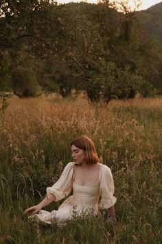 a woman is sitting in the tall grass