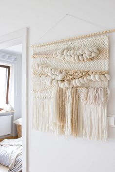 a white wall hanging with macrame beads and tassels