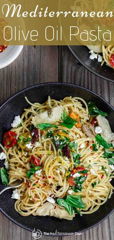 two black plates with pasta and vegetables on them, one has fettuccine