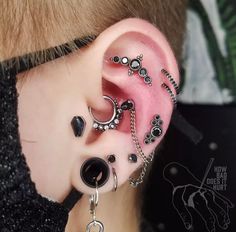 a person with some piercings on their ear and one is wearing an ear chain