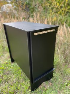 a black box sitting on top of a grass covered field