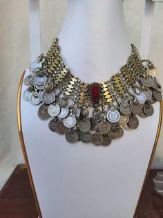 Afghan jewelry is famous for its beautiful and traditional handwork. The jewelry piece is embellished using a number of items such as metal nells, coins, stones, threads etc. these tribal jewelry sets share a link to their cultural values and traditions. This chunky set includes a heavily embellished coin choker. The arrangement of old coins on this whole set gives it a very classic traditional vibe. These handmade pieces can be a slightly bit different from the one in the image. This could be a Vintage Coin Necklaces For Festival, Vintage Metal Coin Necklace, Handmade, Vintage Handmade Metal Coin Necklace, Bohemian Silver Choker In Brass, Handmade Metal Coin Necklace For Festival, Vintage Silver Coin Necklace For Festivals, Antique Coin-shaped Metal Jewelry, Antique Coin Shaped Metal Jewelry, Bohemian Coin Necklace In Metal