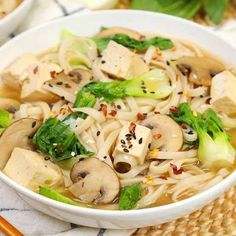 two bowls filled with noodles, mushrooms and broccoli next to chopsticks