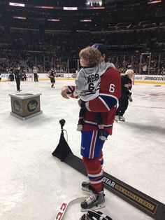 a hockey player is holding his son on the ice