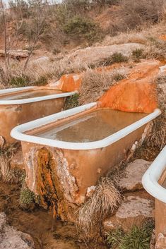 several old bathtubs are sitting on the rocks