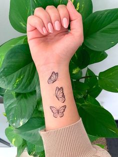 a woman's wrist tattoo with three butterflies on the left side of her arm