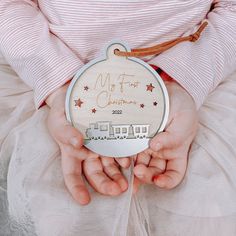 a person holding a wooden ornament with the words my first christmas on it