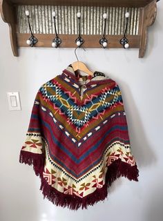 Infuse a touch of boho flair into your closet with our enchanting artisanal ponchos. Meticulously fashioned by our skilled craftsmen in Ecuador, these ponchos exhibit a pullover style accompanied by a hood, and they boast an unparalleled tribal pattern for a truly distinctive look. Dimensions:  Length: 32 in (with fringe 36 in) Width: 41 in ♥ Experience the comfort of our exquisite tribal ponchos, crafted for both warmth and durability to accompany you through your everyday adventures. OUR MISSI Bohemian Hooded Brown Poncho, Bohemian Multicolor Poncho For Fall, Multicolor Bohemian Poncho For Fall, Bohemian Winter Cape One Size, Bohemian Shawl Cape For Fall, Bohemian Poncho Cape, Bohemian Poncho Cape One Size, Bohemian Alpaca Shawl Cape, Bohemian Alpaca Shawl