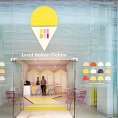 an ice cream shop with yellow and pink colors on the front glass walls, along with two people standing at the counter