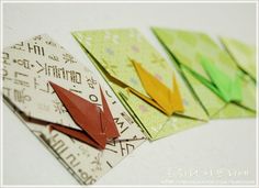 four origami cranes sitting on top of each other in different colors and sizes