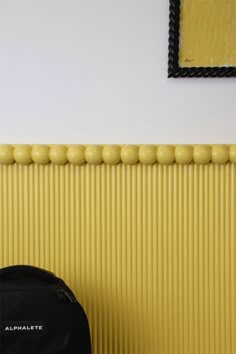 a black backpack sitting in front of a wall with yellow and white stripes on it