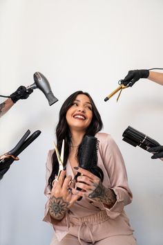 a woman holding a hair dryer in front of her face with many hairdryers around her