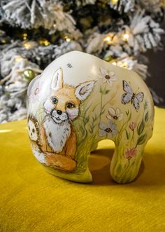 an animal figurine sitting on top of a yellow table cloth next to a christmas tree