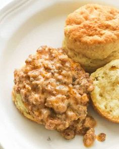 three biscuits and one biscuit on a white plate with some type of food in the middle