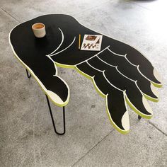 a bird shaped table with a cup on it