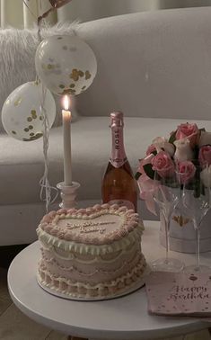 a table topped with a cake next to a bottle of wine and glasses filled with pink roses