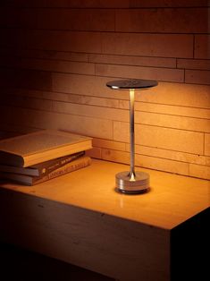 a table lamp sitting on top of a wooden desk next to a stack of books