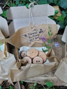 several different types of buttons in a box on the ground with leaves and flowers around them