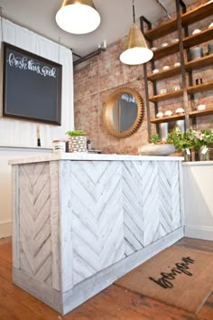 a white counter sitting inside of a store next to a brick wall and wooden shelves