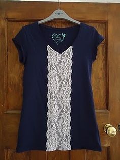 a blue shirt with white lace on it hanging from a wooden door hanger in front of a brown door