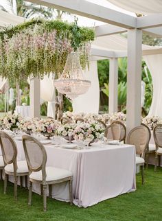 an outdoor dining area with tables, chairs and chandelier hanging from the ceiling