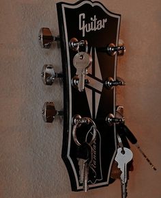 a guitar hanging on the wall with keys attached to it