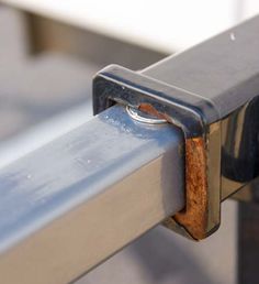 a close up of a metal rail with a rusted piece of wood sticking out of it