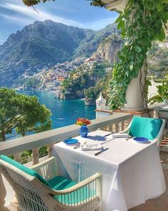 an outdoor dining area with table and chairs overlooking the water