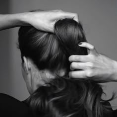 a woman with her hands on top of her head while she is combing her hair