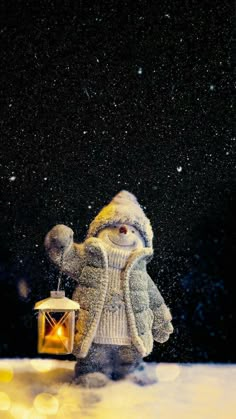 a snowman holding a lantern in the snow