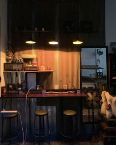 an empty bar with stools and lights in the corner, next to a fan