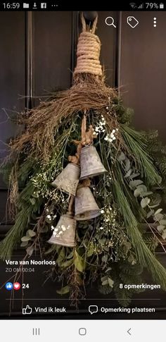 a bunch of bells that are hanging from a tree with greenery on it's sides