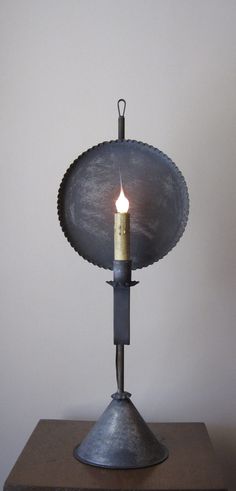 a candle is lit on top of a metal object that looks like a lamp holder