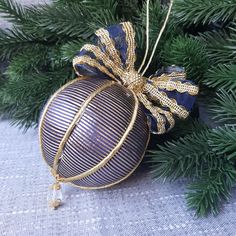 an ornament hanging from a christmas tree with gold ribbon on it's side