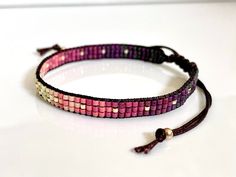 a purple and pink beaded bracelet on a white surface