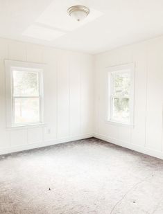 an empty room with two windows and no carpet