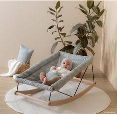 a baby sitting in a rocking chair next to a potted plant