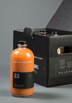 an orange bottle sitting next to a black box on a gray surface with the lid open