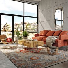 a living room filled with lots of furniture next to large windows and a desert landscape