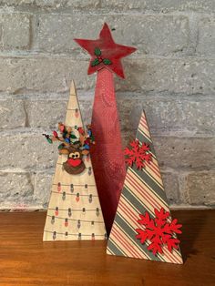 two small wooden christmas trees sitting on top of a table next to a brick wall