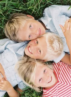 two boys laying in the grass with their arms around each other