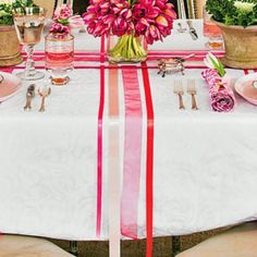 the table is set with pink flowers and silverware