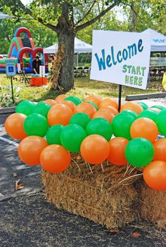 there are many balloons in the hay with a sign that says welcome to start here